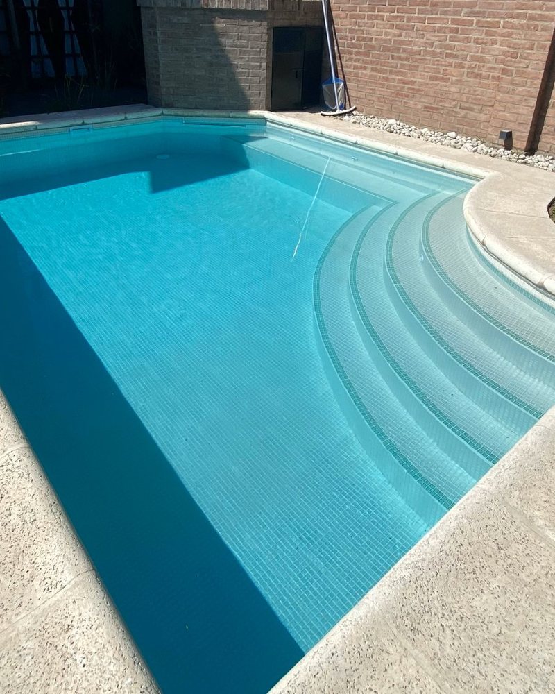 Pileta turquesa con escalera curva revestida con venecitas Neobind
